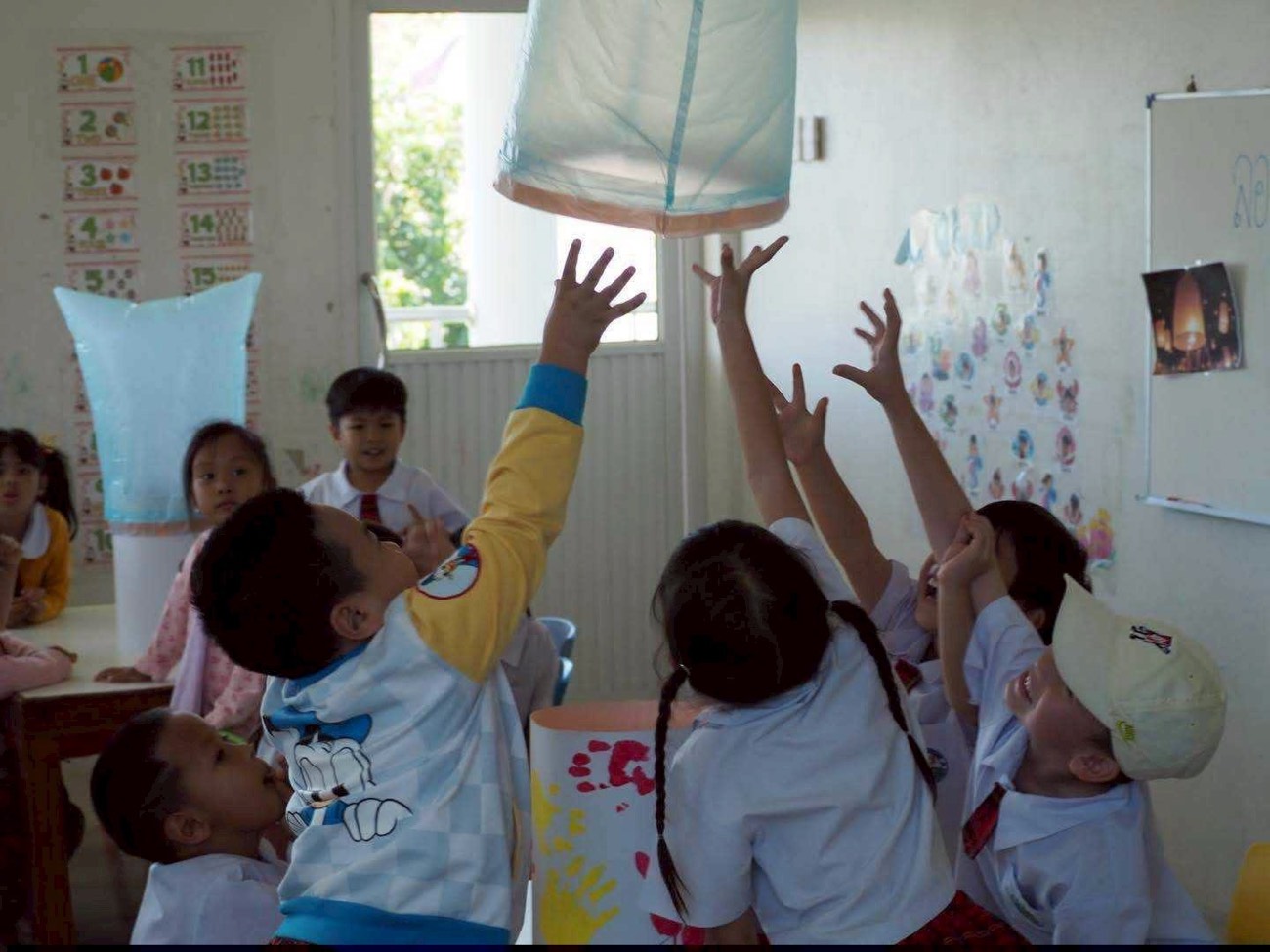 เด็ก ๆ เอื้อมมือไปหาโคมลอยที่ประดิษฐ์เอง
